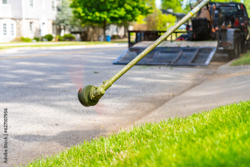 Landscaping Company Tending to A Front Lawn and Flower Bed Cutting Grass and Blowing Debris