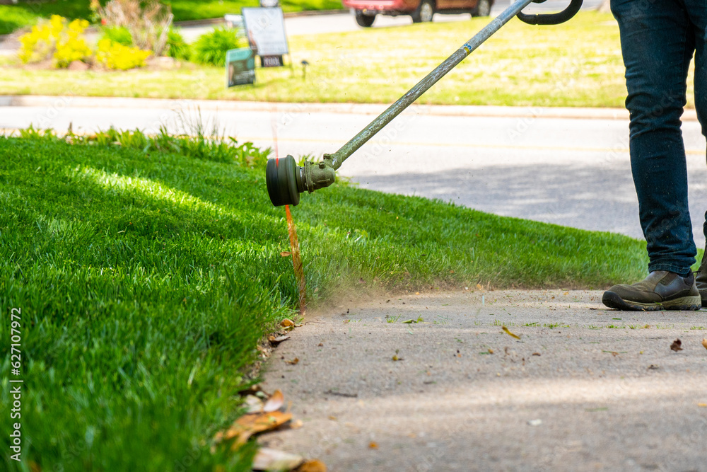 Landscaping Company Tending to A Front Lawn and Flower Bed Cutting Grass and Blowing Debris