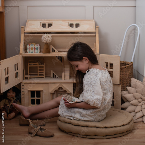 wooden house for dolls. girl playing in children's room