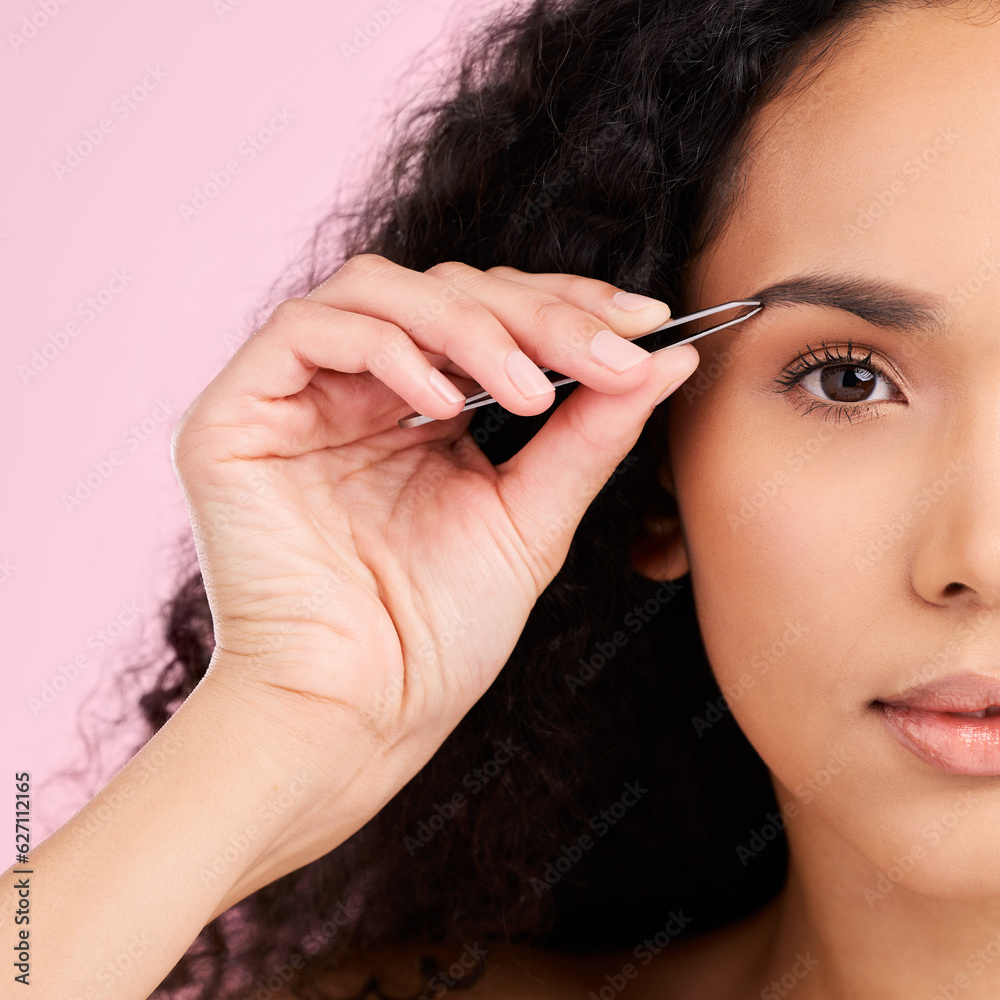 Obraz premium Face, beauty and woman with tweezer for eyebrow, skincare and grooming isolated on a pink background. Natural portrait, facial plucking and hair removal of serious model for wellness and aesthetic