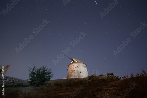 Ruin windmill in the night sky. A view of the stars of the Milky Way with a mountain top in the foreground. Night sky nature summer landscape. Perseid Meteor Shower observation photo