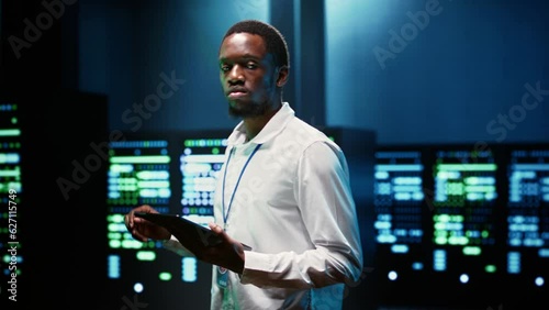 African american supervisor in server farm using tablet to find firewall misconfigurations affecting rackmounts performance and connectivity, leading to slow data transfer rates photo