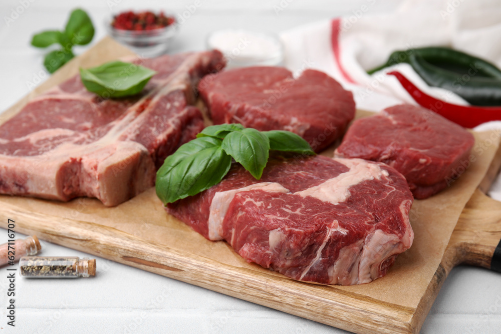 Cut fresh beef meat and basil leaves on white table, closeup