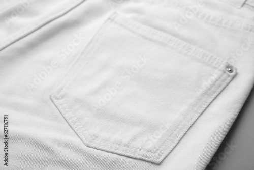 White jeans with pocket on grey background, closeup
