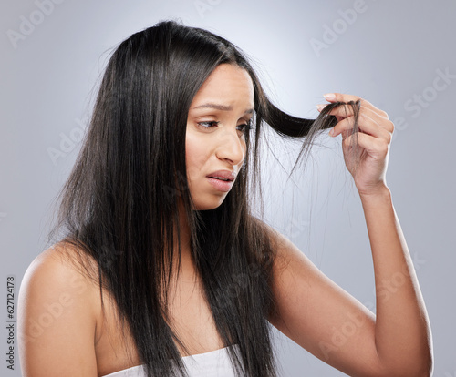 Hair, worry and woman with crisis in studio for split ends, haircare crisis and weak tips on gray background. Beauty, salon and face of upset female person with frizz, dry texture and loss problem