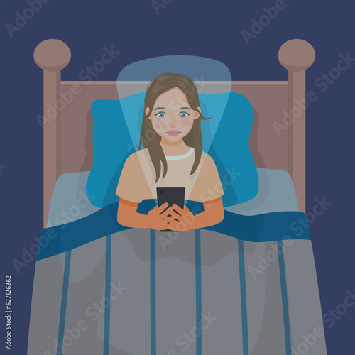 Young woman using smartphone lying in the bed in the dark room
