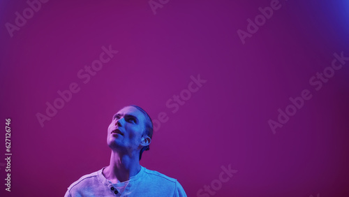 Neon people. Advertising background. Information presentation. Blue purple color light curious impressed guy reading invisible text on dark empty space.