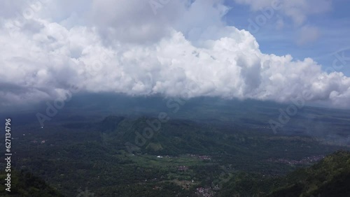 White puffy clouds over a green tropical valley of balinese villages amid forests and mountains near lahangan sweet, Bali. Aerial dolly photo