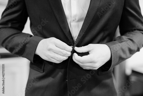 Man is buttoning his suit jacket in black and white
