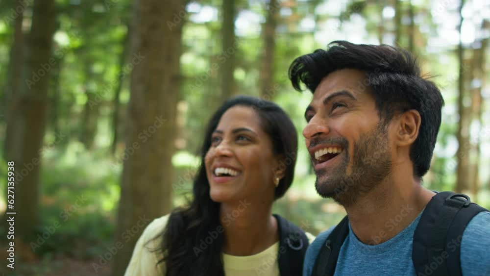 Couple wearing backpacks on walk exploring nature in summer forest together - shot in slow motion