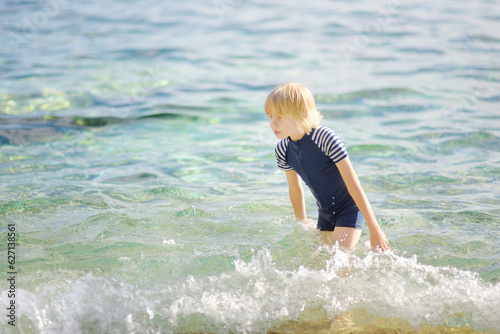 Cute preteen boy is bathing in a sea. Fun beach holiday for children. Summer vacation for kids.