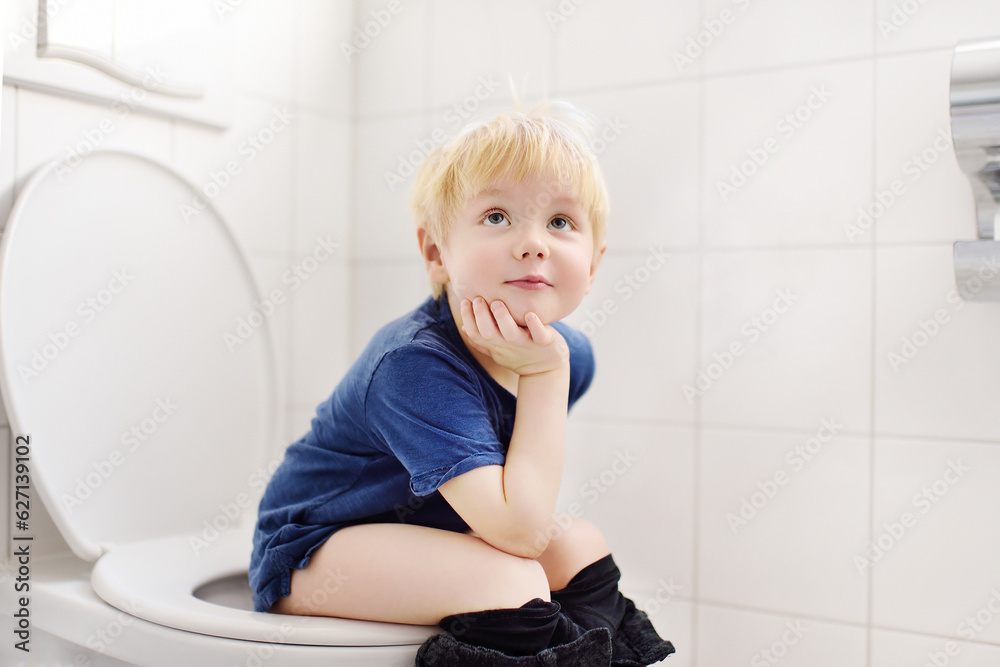 Cute little boy in restroom. Toddler child is training use toilet. Treatment of constipation of little kids. Teaching children of hygiene Cute little boy in restroom. Toddler child is training use toilet. Treatment of constipation of little kids. Teaching children of hygiene