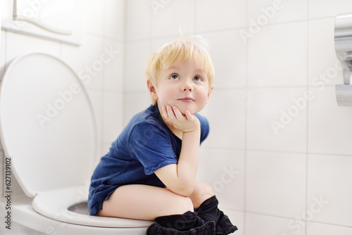 Cute little boy in restroom. Toddler child is training use toilet. Treatment of constipation of little kids. Teaching children of hygiene photo