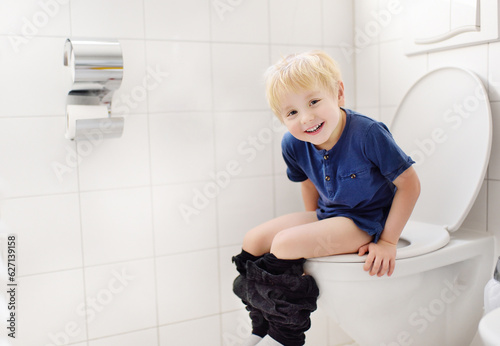 Cute little boy in restroom. Toddler child is training use toilet. Treatment of constipation of little kids. Teaching children of hygiene photo