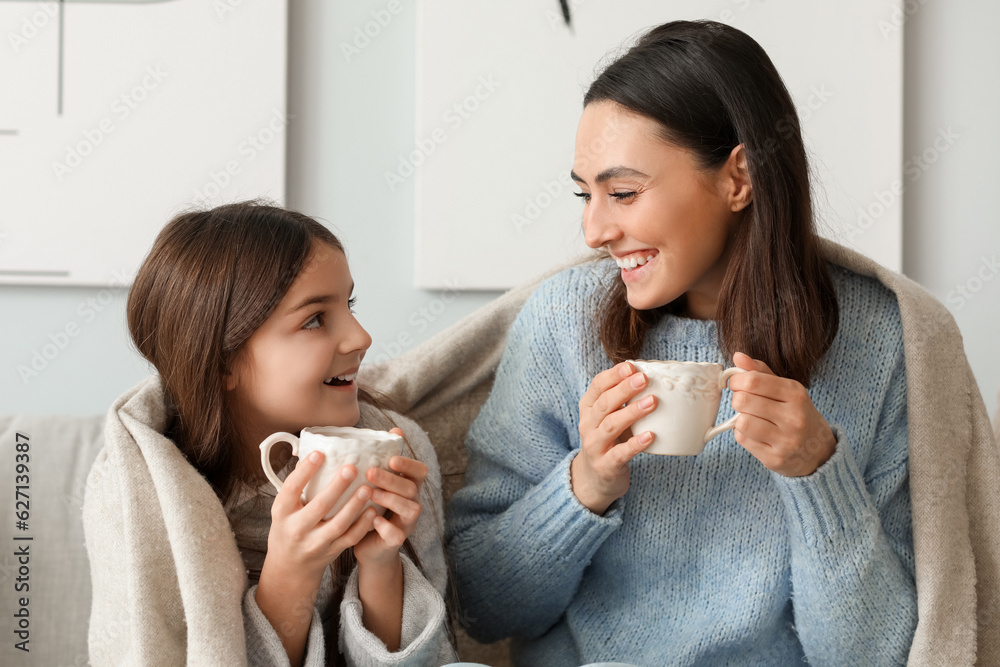 Little girl and her mother with cups of tea sitting at home Little girl and her mother with cups of tea sitting at home