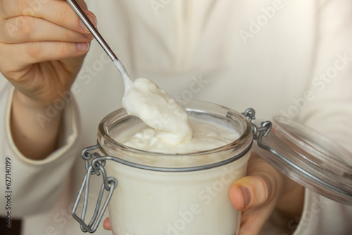 Unrecognizable woman eating from Glass jar natural organic homemade yogurt. Immunity-boosting ingredients. Concept of healthy eating breakfast of Greek yogurt. Fermenting superfood