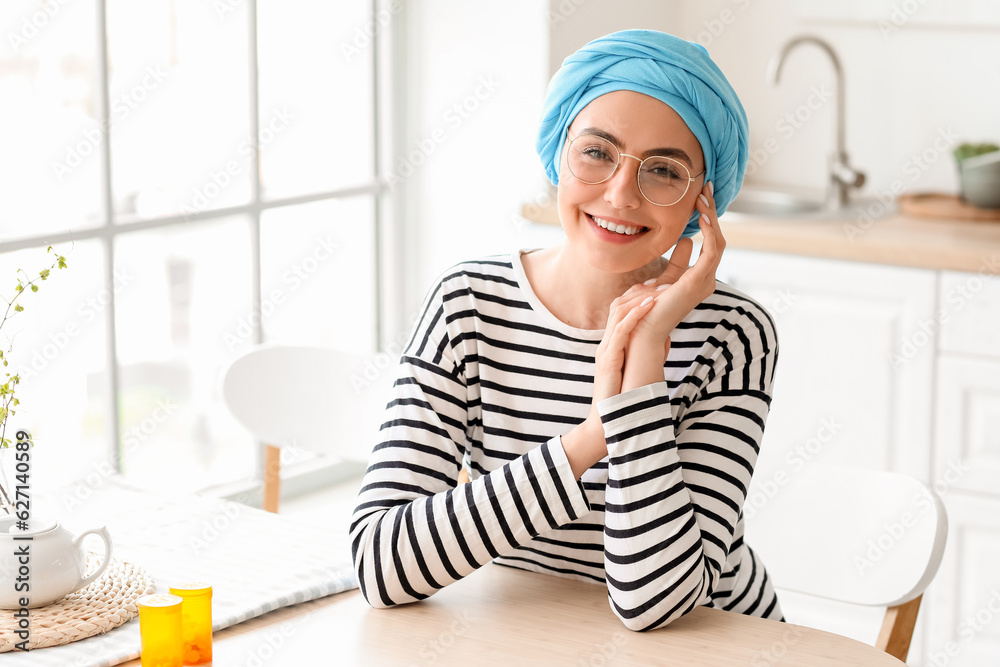 Young woman after chemotherapy sitting at table in kitchen Young woman after chemotherapy sitting at table in kitchen