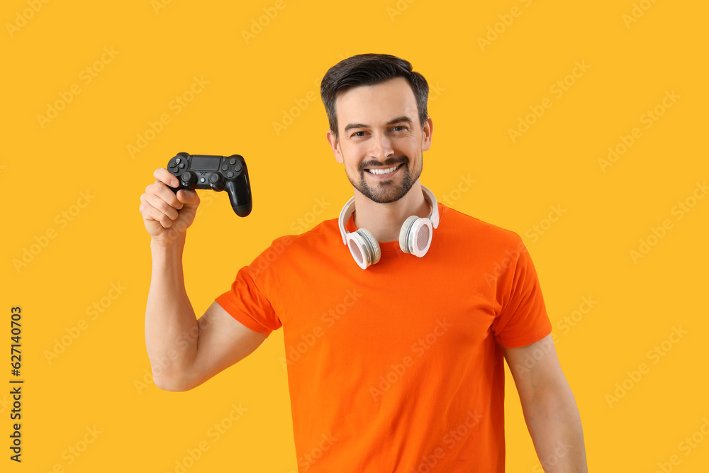 Handsome man with game pad on yellow background Handsome man with game pad on yellow background
