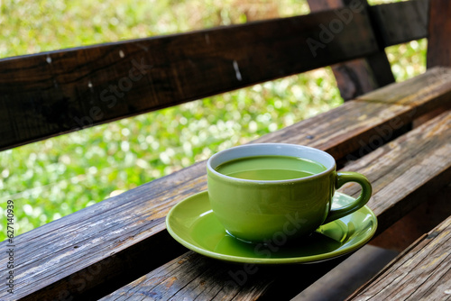 a cup of milk green tea on the table beside lake. the addition of milk to green tea may help mitigate the potential bitterness or astringency of some green teas, making it more enjoyable.