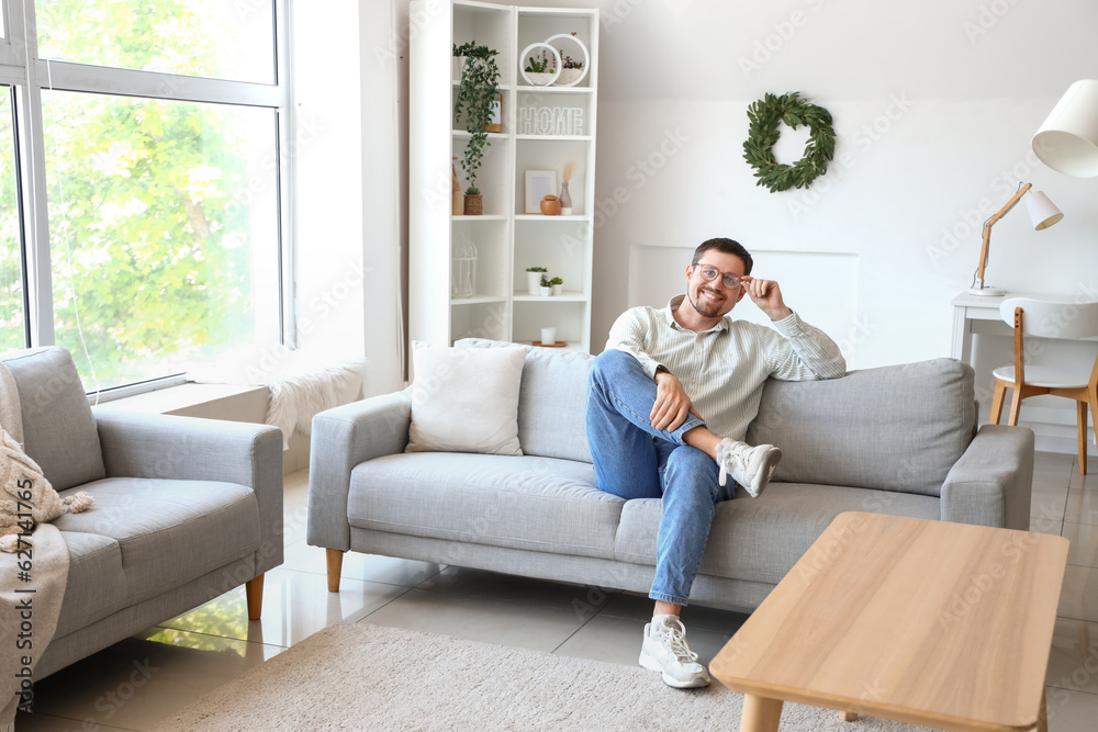 Handsome man in stylish eyeglasses sitting on sofa at home Handsome man in stylish eyeglasses sitting on sofa at home