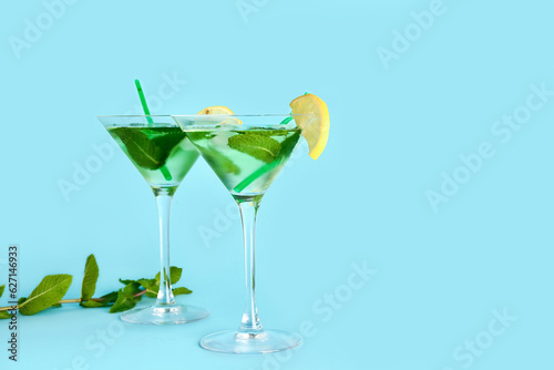 Glasses of tasty mojito on color background