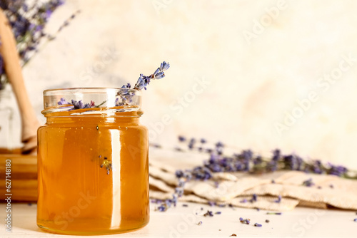 Jar of sweet lavender honey and flowers on white wooden table