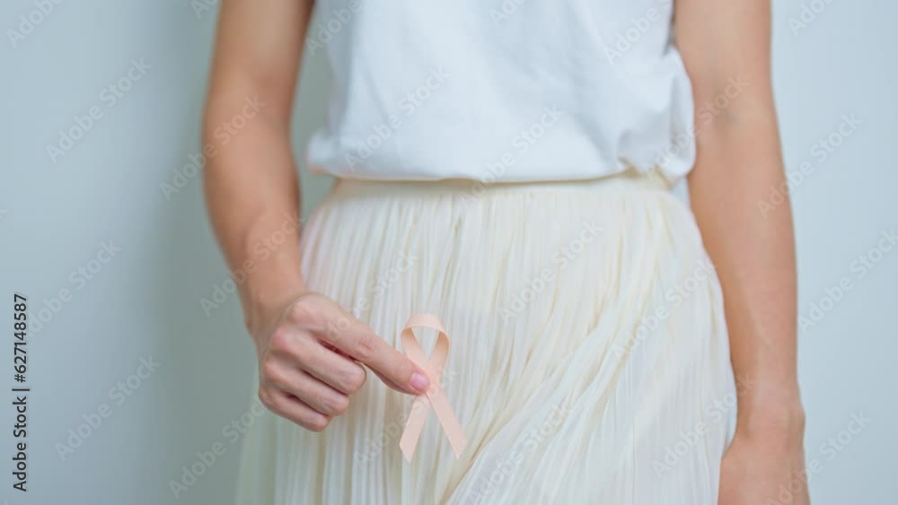 Woman holding Peach Ribbon on abdomen for September Uterine Cancer Awareness month. Uterus and Ovaries, Cervix, Endometriosis, Hysterectomy, Uterine fibroids, Reproductive and World cancer day concept