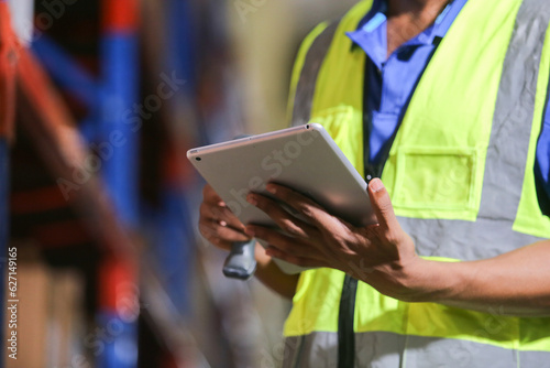 Close up Tablet, Man professional worker wearing safety uniform and hard hat using digital tablet inspect product on shelves in warehouse. Male worker check stock inspecting in storage logistic. © eakgrungenerd