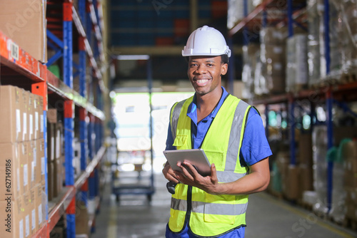 Portrait man american african professional worker wearing safety uniform using digital tablet inspect product on shelves in warehouse. Worker check stock inspecting in storage logistic factory.