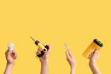 Electrician hands with light bulb and tools on yellow background