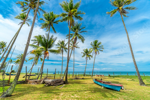 Beautiful tropical beach with fisherman village, coconut palm tree and blue sky..