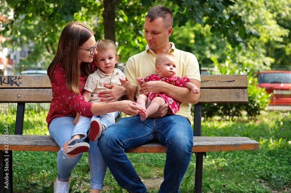 Family with two children sitting on a bench in the park Family with two children sitting on a bench in the park