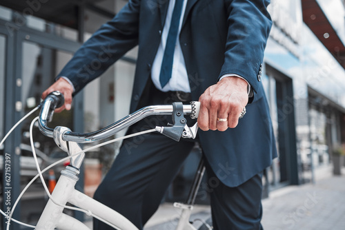Hands, bicycle and businessman cycling in the city or riding for eco friendly travel, transport or commute to office, building or work. Man, driving and bike for carbon neutral footprint in town