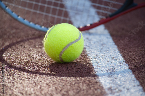 Tennis racquet and yellow tennis ball on outdoor court
