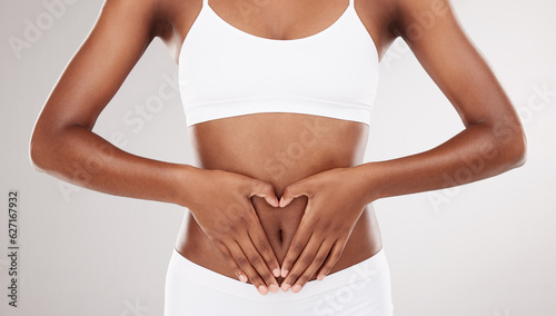 Heart shape, hands and stomach of a woman for health and wellness on a white studio background. Fitness, gut and diet of aesthetic female model for weight loss, balance or digestion and motivation photo