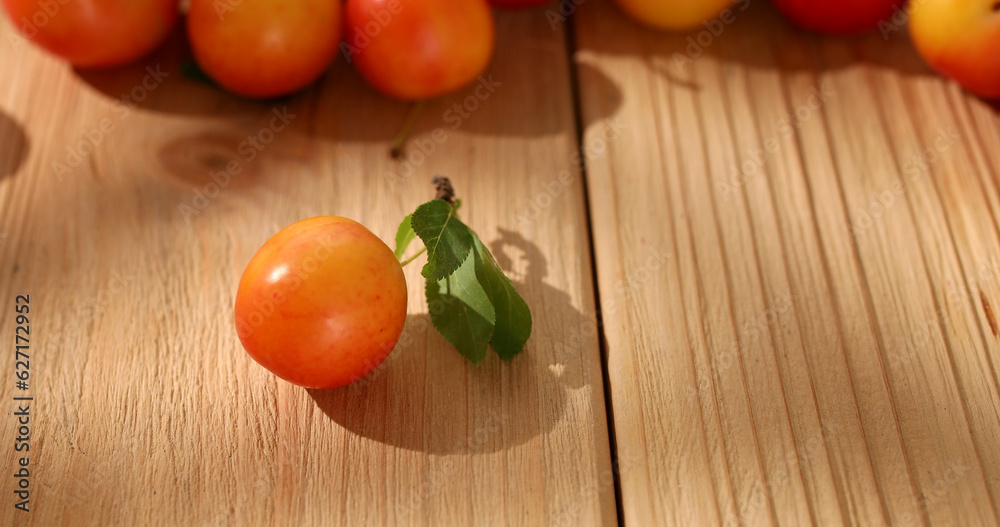 red cherry plum with a leaf on a wooden table. fresh fruits on a sunny day. veggie food. High quality photo. red cherry plum with a leaf on a wooden table. fresh fruits on a sunny day. veggie food. High quality photo.