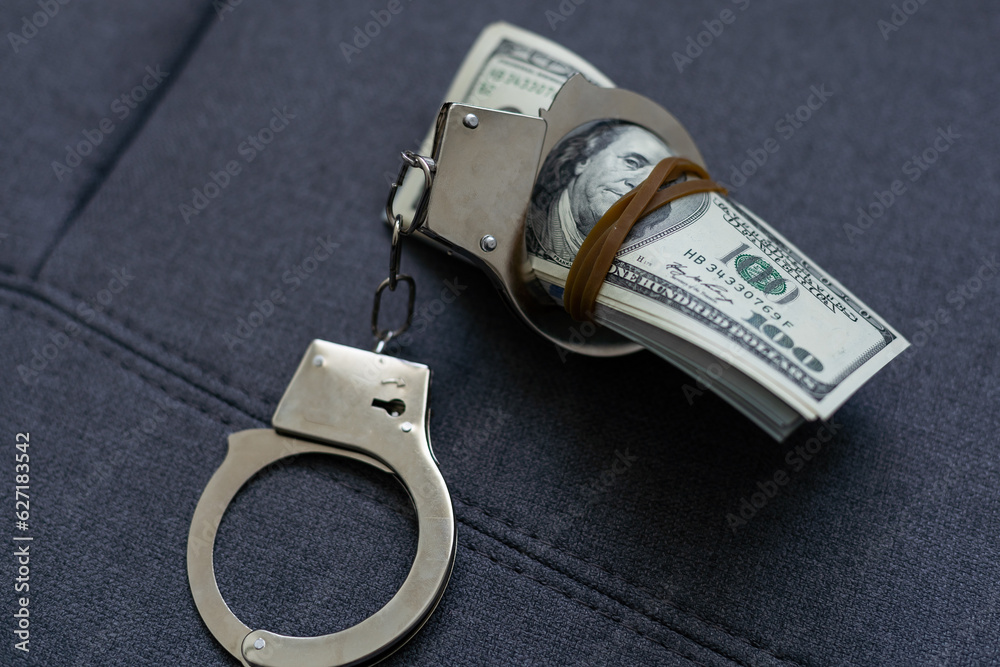 The handcuffs are on hundred-dollar bills. Power and bribery. Criminal ransom. Criminal earnings. Business concept. The concept of wealth The handcuffs are on hundred-dollar bills. Power and bribery. Criminal ransom. Criminal earnings. Business concept. The concept of wealth