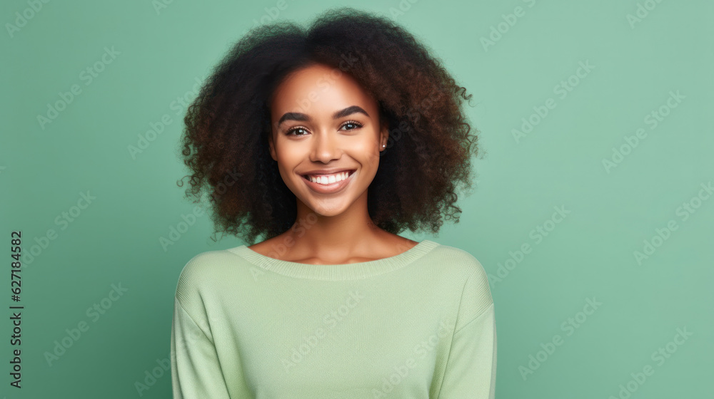 Fototapeta premium Portrait of a smiling young african woman wearing sweater standing isolated over green background