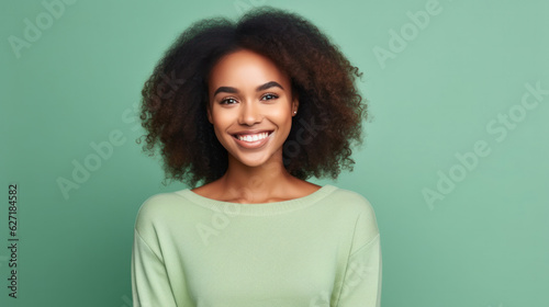 Portrait of a smiling young african woman wearing sweater standing isolated over green background