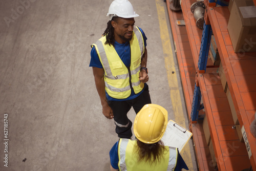 High angle view of warehouse workers in hardhats lifting boxes at warehouse photo