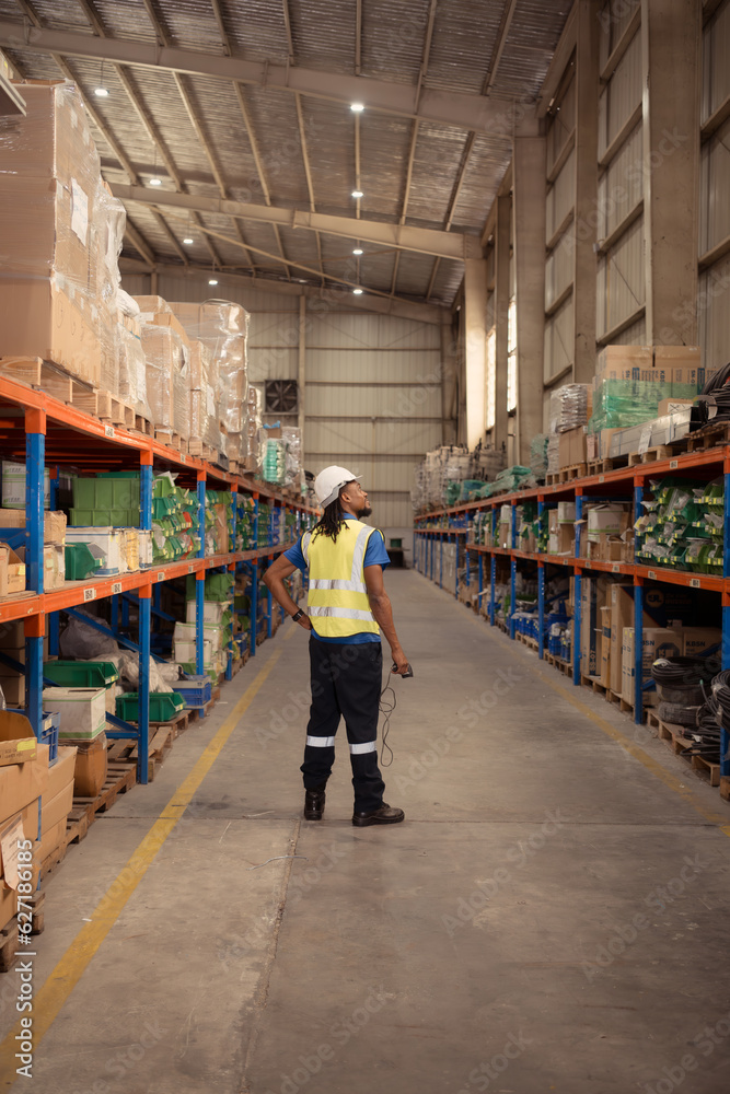 Portrait of male worker wearing hardhat and reflective vest holding hand scanner working in warehouse