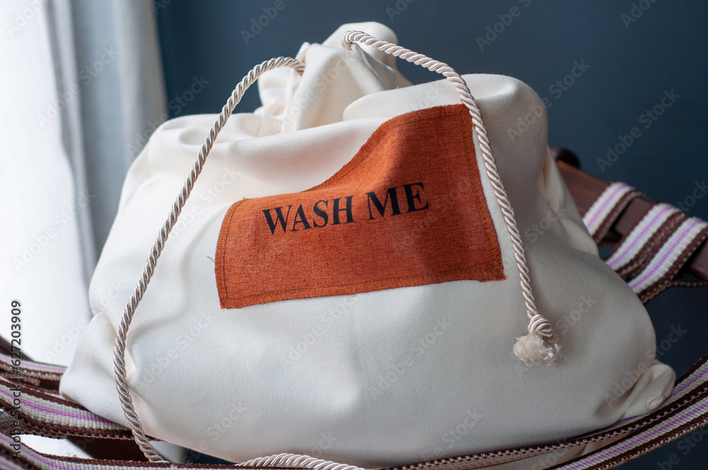 Naklejka premium close up, crop white laundry bag with text 'wash me'. hotel concept. 
