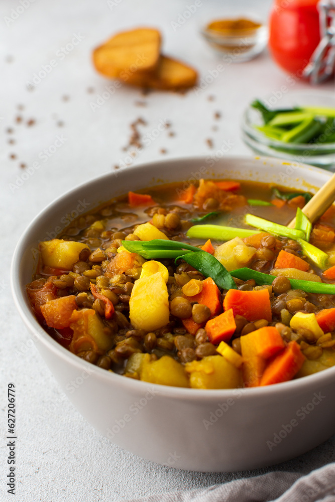 Healthy vegetarian lunches, brown lentil soup with tomatoes and carrots, green onions, potatoes and curry spices, toasted croutons, top view Healthy vegetarian lunches, brown lentil soup with tomatoes and carrots, green onions, potatoes and curry spices, toasted croutons, top view