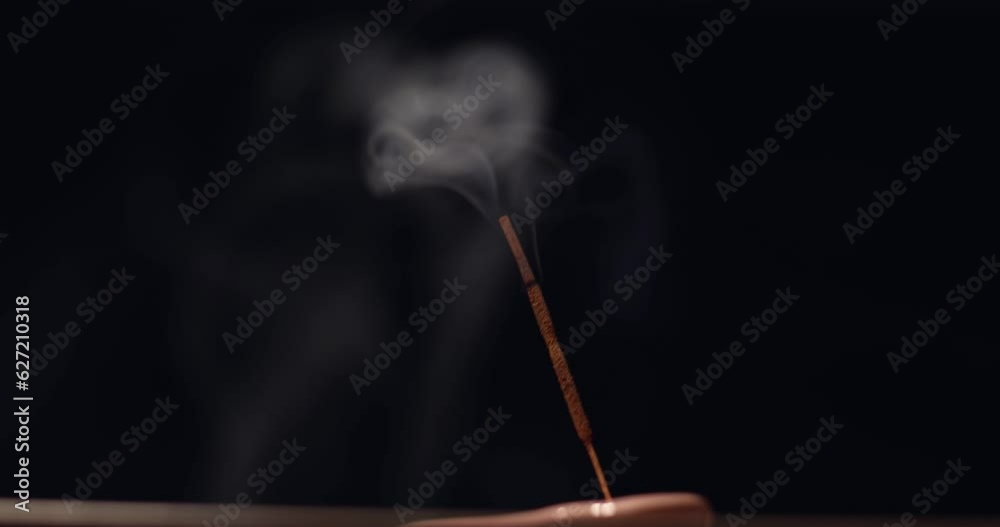 Incense stick emitting smoke against the black background. Therapeutic oriental smoke. Aromatherapy, relaxation and yoga. Smoke from aroma sticks moves. Incense stick emitting smoke against the black background. Therapeutic oriental smoke. Aromatherapy, relaxation and yoga. Smoke from aroma sticks moves.