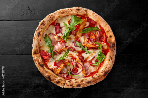 Pizza with pelati sauce, cheese, sausages, bacon, sous vide chicken, onion, chili pepper photo