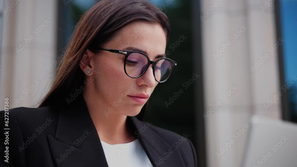 Close up off elegant businesswoman is working remotely with a wireless portable computer. Girl is typing on laptop, online chatting, browsing a programmer app outdoors near an office company building. Close up off elegant businesswoman is working remotely with a wireless portable computer. Girl is typing on laptop, online chatting, browsing a programmer app outdoors near an office company building.