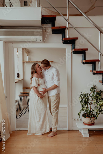 Man hugs his pregnant woman in a bright room