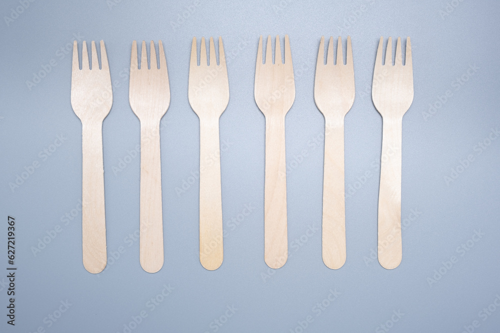 Wooden disposable fork on a gray background close-up. Environmentally friendly product.