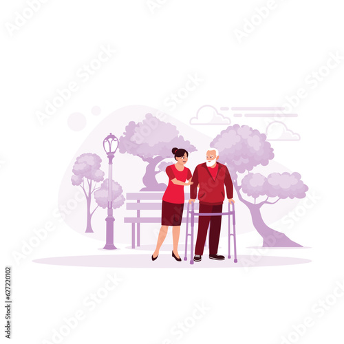 A woman helps an older adult to practice walking using a walker. A young female nurse in a nursing home cares for a disabled senior male patient. Caregivers provide physical therapy. 