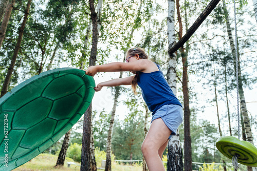 Low angle view of a cute little girl having fun at playground play with sandboxes with the swing. Recreation of children with special needs concept. photo